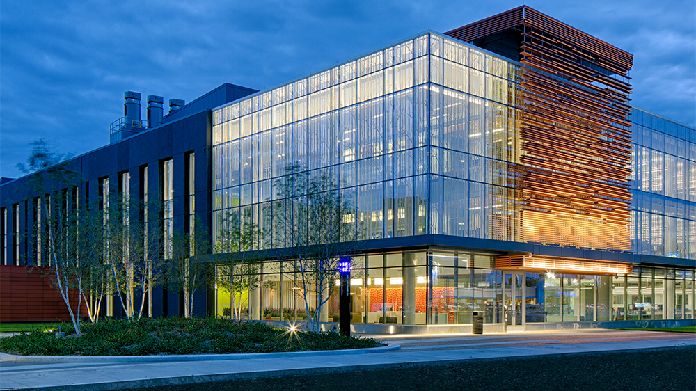 Exterior of the Integrative Biosciences Center at dusk highlighting the full height glass windows and modern architecture.